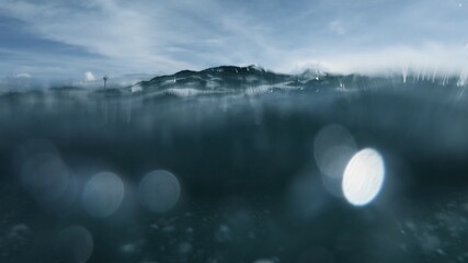 Wave on moving water surface close up in the middle of the screen.  Under Water Surface in the middle of the sea