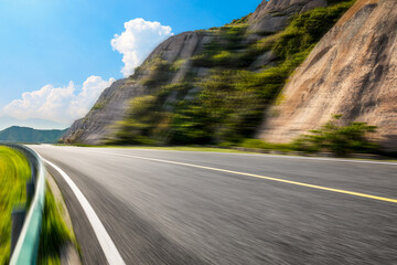 Motion blurred asphalt road and mountain natural landscape on a sunny day.