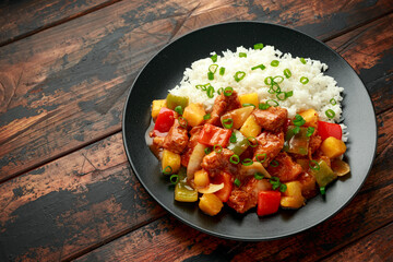 Pineapple and Chicken in sweet and sour sauce with bell pepper, rice and spring onion in black plate