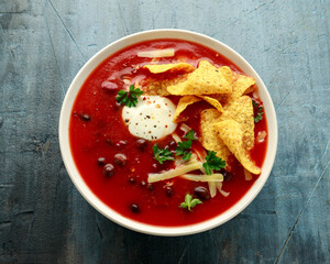 Mexican Chilli bean soup with yogurt, cheese, lime and tortilla chips in white bowl