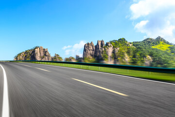 Fototapeta na wymiar Motion blurred asphalt road and mountain natural landscape on a sunny day.