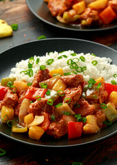 Pineapple and Chicken in sweet and sour sauce with bell pepper, rice and spring onion in black plate