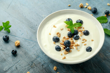 Greek yogurt with granola and blueberries in white bowl. Healthy breakfast food or snack