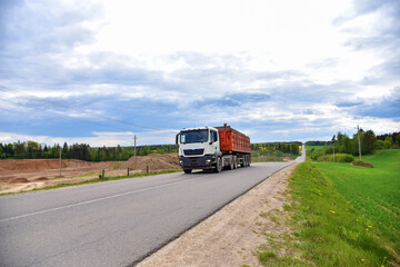Fototapeta na wymiar Truck with tipper semi trailer transported sand from the quarry on driving along highway.