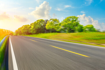 Fototapeta premium Motion blurred asphalt road and green tree landscape.