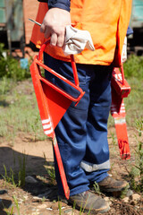 Fototapeta premium a railway worker in an orange signal vest and arms holds in his hand a red brake shoe