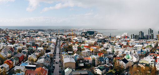 Beautiful wide-angle aerial view of Reykjavik, Iceland with harbor and skyline mountains and scenery beyond the city, seen from the observation tower of Hallgrimskirkja Cathedral.