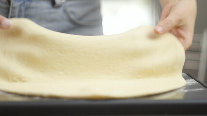 Cooking pizza. The chef prepares the pizza dough. A man or woman is engaged in home business preparing a delicious pizza