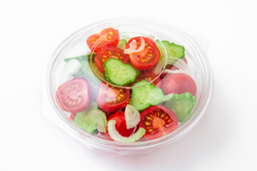 Salad in plastic package for take away or food delivery isolated on a white background. Nutritional Diet Snack with tomatoes, cucumbers, onions.