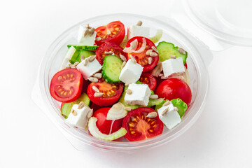 Salad in plastic package for take away or food delivery isolated on a white background. Nutritional Diet Snack with tomatoes, cucumbers, feta cheese and sunflower seeds