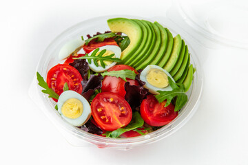 Salad in plastic package for take away or food delivery isolated on a white background. Nutritional Diet Snack with tomatoes, avocado, quail egg.