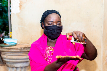 corona virus. senior african woman wearing face mask applying hand sanitizer preventing the spread of covid 19 virus. elderly black woman wore face mask