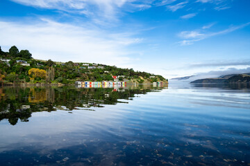 Fototapeta premium Colorful Boat Sheds with beautiful reflection on daytime at Duvauchelle, Akaroa Harbour on Banks Peninsula in South Island, New Zealand.