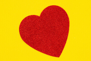 Red heart on yellow felt material background