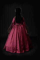 A young woman in a red Tudor dress against a black bacdrop - obrazy, fototapety, plakaty