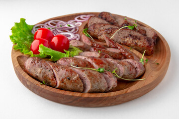 Homemade sausage in a natural shell with onions and sauce. Banquet festive dishes. Gourmet restaurant menu. White background.