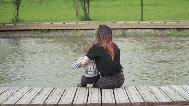 Boy with mom sit on a wooden pier