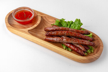 Hunting sausages with sauce on a wooden stand. Banquet festive dishes. Gourmet restaurant menu. White background.