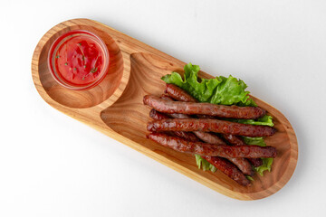 Hunting sausages with sauce on a wooden stand. Banquet festive dishes. Gourmet restaurant menu. White background.