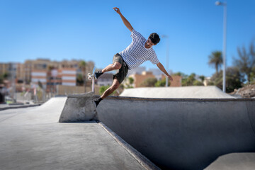 Hombre joven patina por el borde de una piscina en un parque de skate. © magui RF
