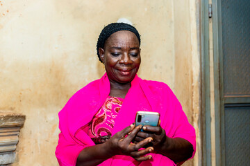 Fototapeta premium cheerful excited old black african woman receiving some good news with her smart phone.happy senior lady using mobile phone