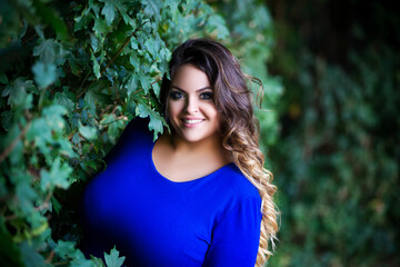 Happy plus size fashion model in blue dress outdoors, fat woman with beauty makeup and hairstyle