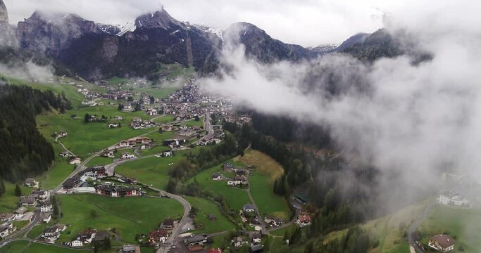 Aerial over Selva Val Gardena during a cloudy overcast day. Flying trough clouds in spring above Wolkenstein