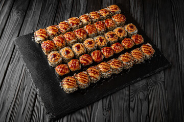 Sushi set with fresh ingredients on black background. Different types of hot fried rolls. Sushi menu. Japanese food. 