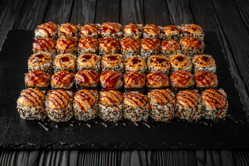 Sushi set with fresh ingredients on black background. Different types of hot fried rolls. Sushi menu. Japanese food. 