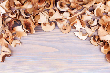 Edible dried mushrooms border on light wooden background closeup top view, dry boletus edulis on wood backdrop frame, brown cap boletus, penny bun, cep, porcino, porcini, white fungus, text copy space
