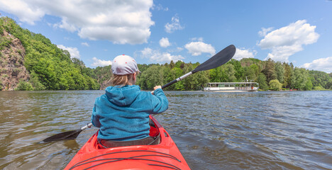 junge Frau paddelt in einem roten Paddelboot / Kajak auf der Zschopau Talsperre Kriebstein in Sachsen bei Lauenhain am Wappenfelsen 