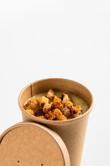 Potato cream soup with croutons in craft containers on a white background. Vegetable soup to go, food delivery