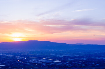 山に沈む夕焼けと河と平野