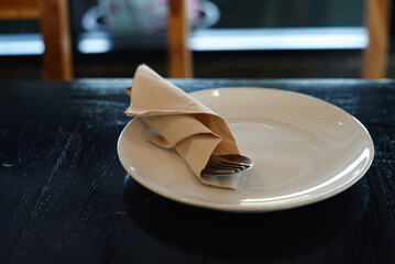 White dish and spoon on wooden table in restaurant