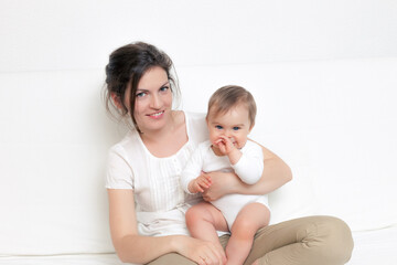 Mother playing with baby on white sofa