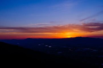 山に沈む夕焼けと河と平野