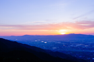 山に沈む夕焼けと河と平野