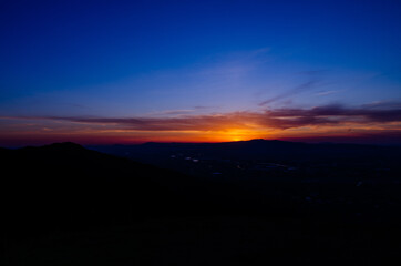山に沈む夕焼けと河と平野