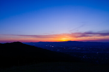 山に沈む夕焼けと河と平野