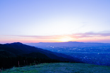 Naklejka premium 山に沈む夕焼けと河と平野