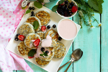 Summer breakfast. Homemade cottage cheese pancakes with poppy seeds, sour cream sauce with strawberries. Top view flat lay background. Copy space.