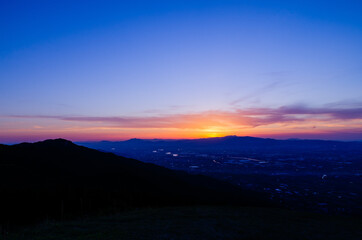 山に沈む夕焼けと河と平野