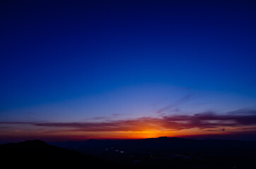 山に沈む夕焼けと河と平野