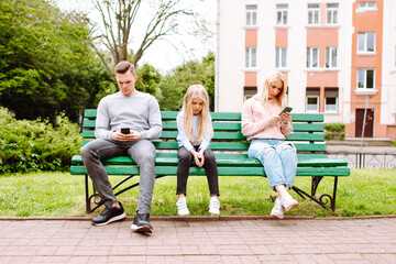 Bad parenting: a child is left sad and unattended while her parents are lost in cellphones. Social...