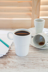 Office workplace with  coffee cup on wooden desk table in front of window with blinds, selective focus