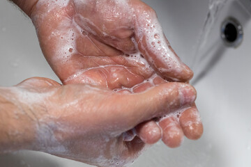 Fototapeta premium Soapy hands under the tap, Personal hygiene, Hand washing, Removal of viruses and bacteria, Basic protection against viruses and bacteria