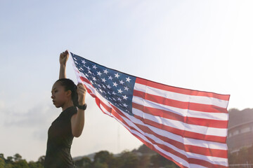 Young asian woman holding American flag on blue sky background