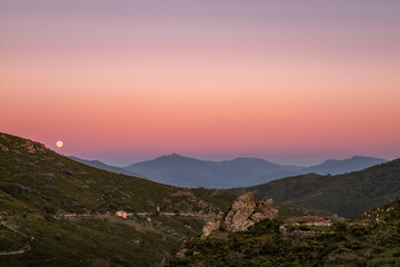 Fototapeta na wymiar Strawberry full moon rising over mountains of Corsica