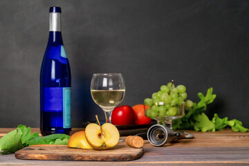 Champagne bottle, glass, grapes and apple on wooden table