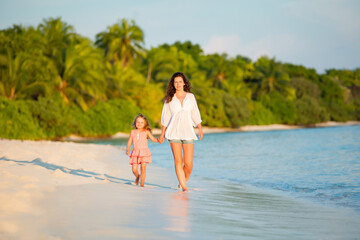 Fototapeta premium Mother and little daughter walking on the beach on Maldives at summer vacation